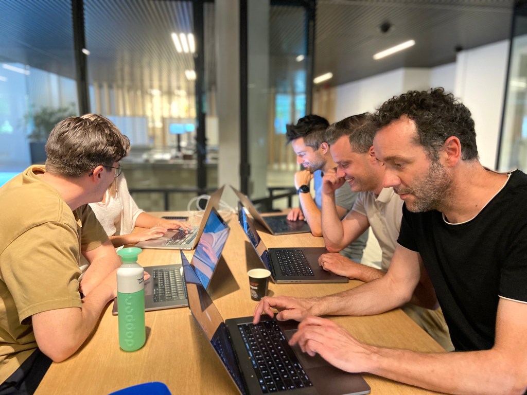 Five people seating at a table facing their laptops testing websites.
