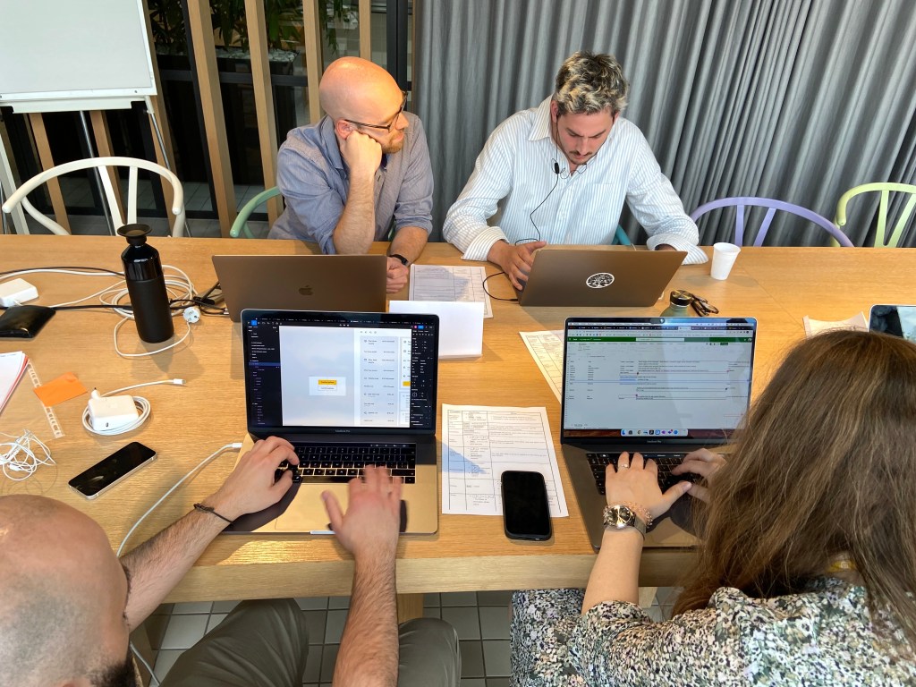 Top view. Four people seating at a table facing their laptops testing websites.