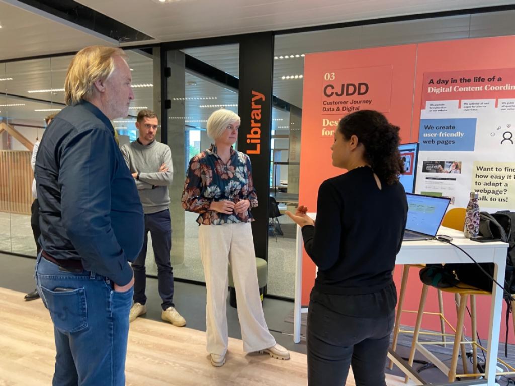 John Porter, Telenet CEO listening to Nadia presenting booth. Both standing.